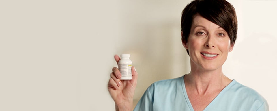 Une femme souriante tenant un flacon de Tylenol