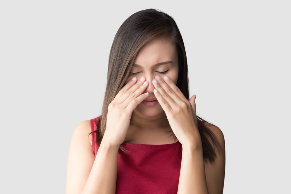 Femme se tenant le nez à cause d'une douleur aux sinus